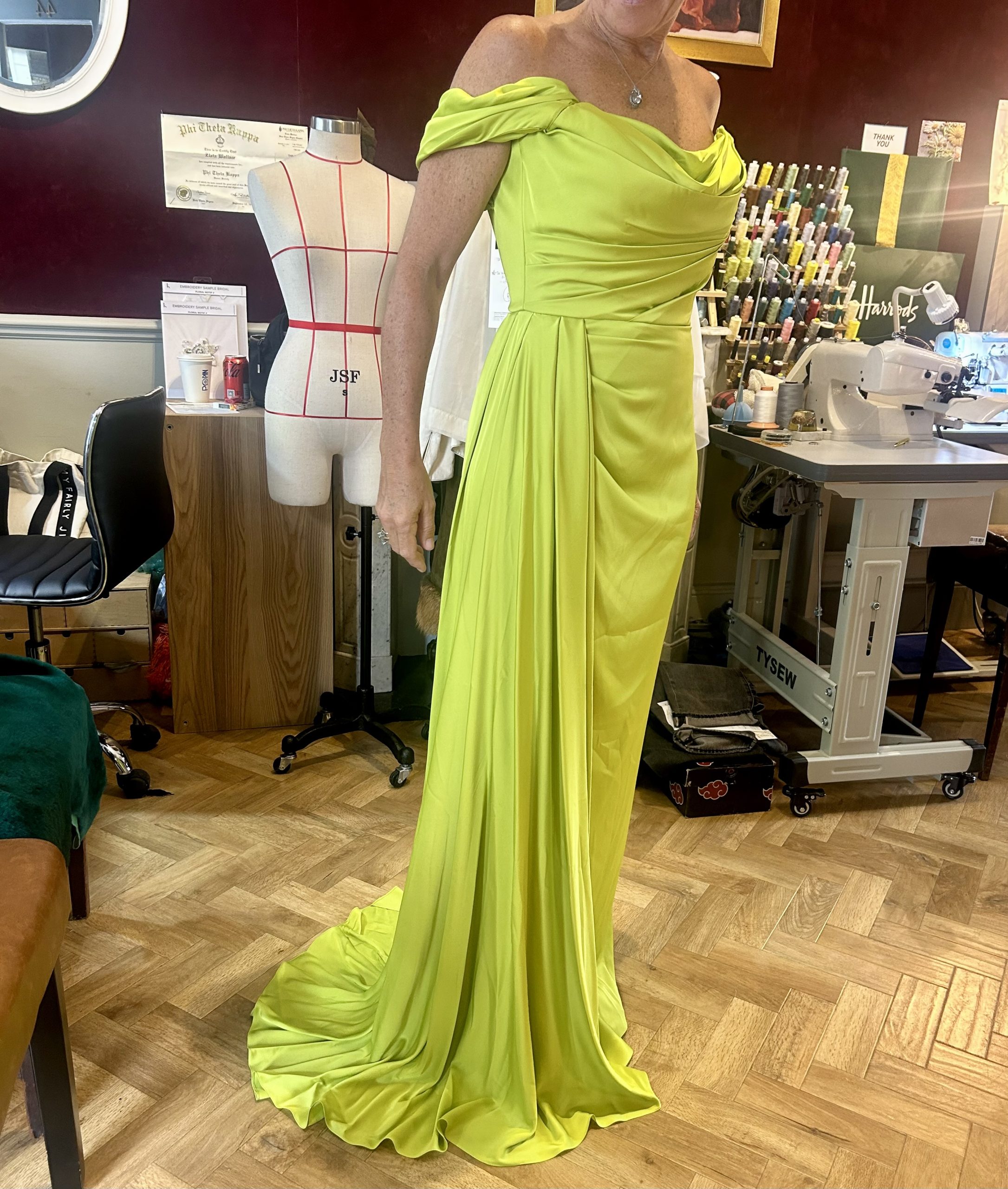 Chartreuse off-the-shoulder evening gown during a luxury bespoke alterations fitting in an atelier.