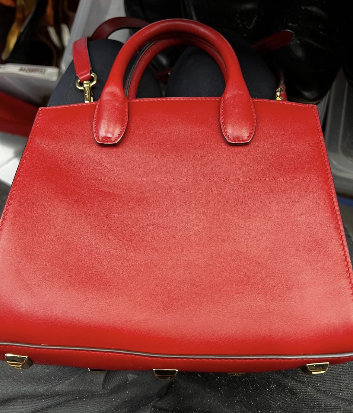 Restored bright red leather handbag with dual handles and gold-toned metal feet.