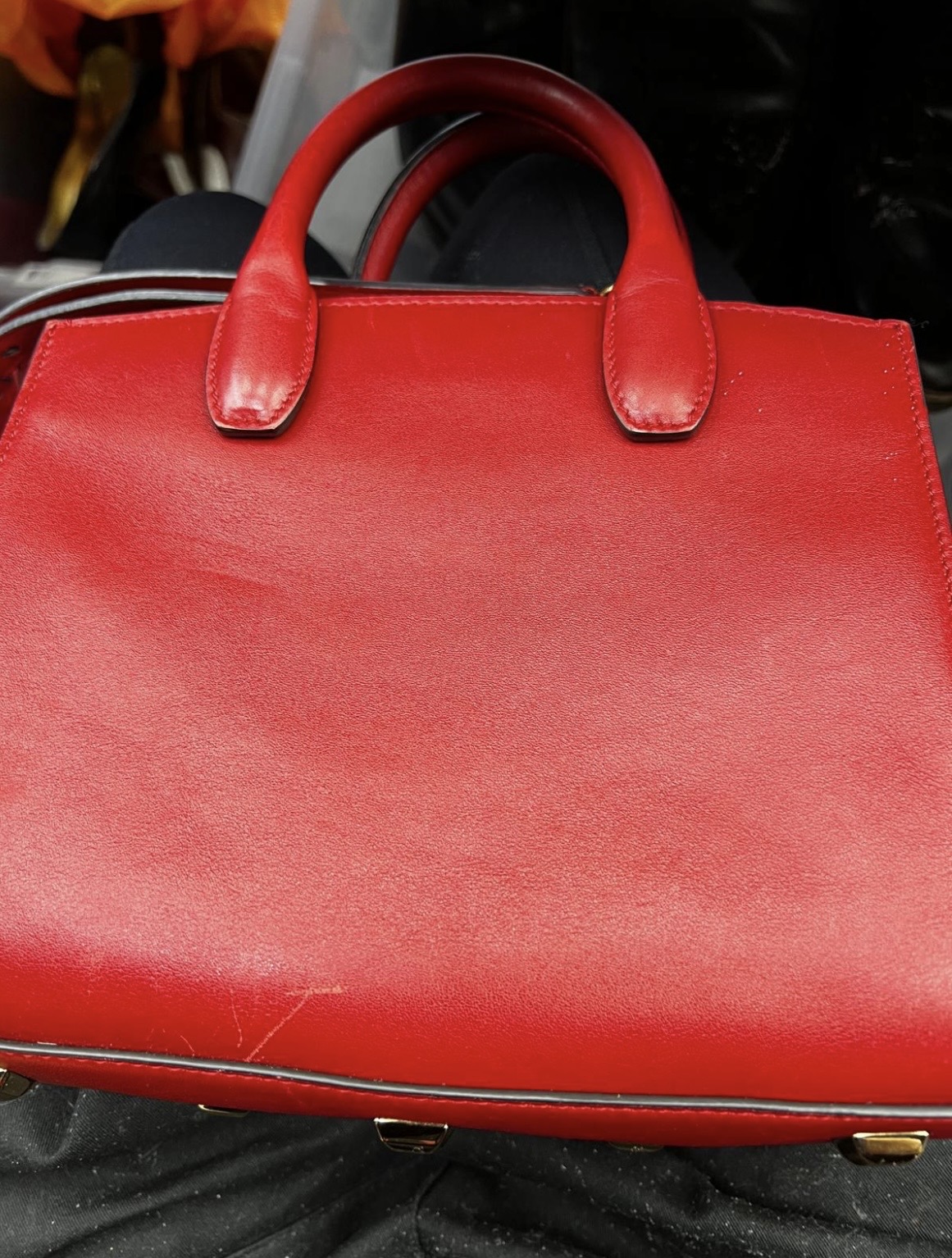Bright red leather handbag with a diagonal scuff mark on the front panel before repair.