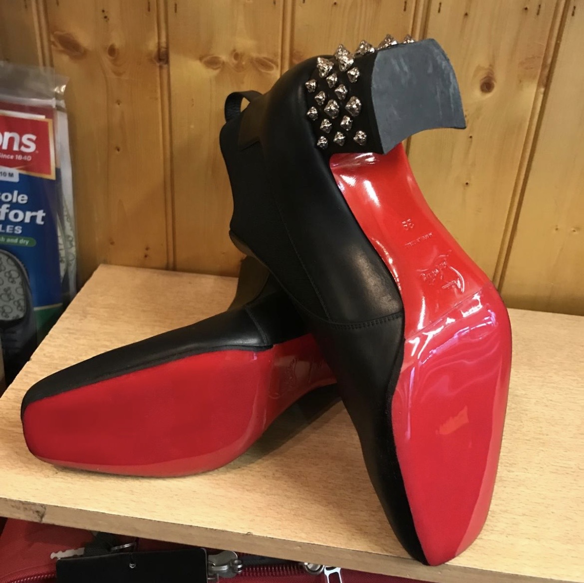 Black leather boots with bright red replacement soles and studded heels after professional repair.