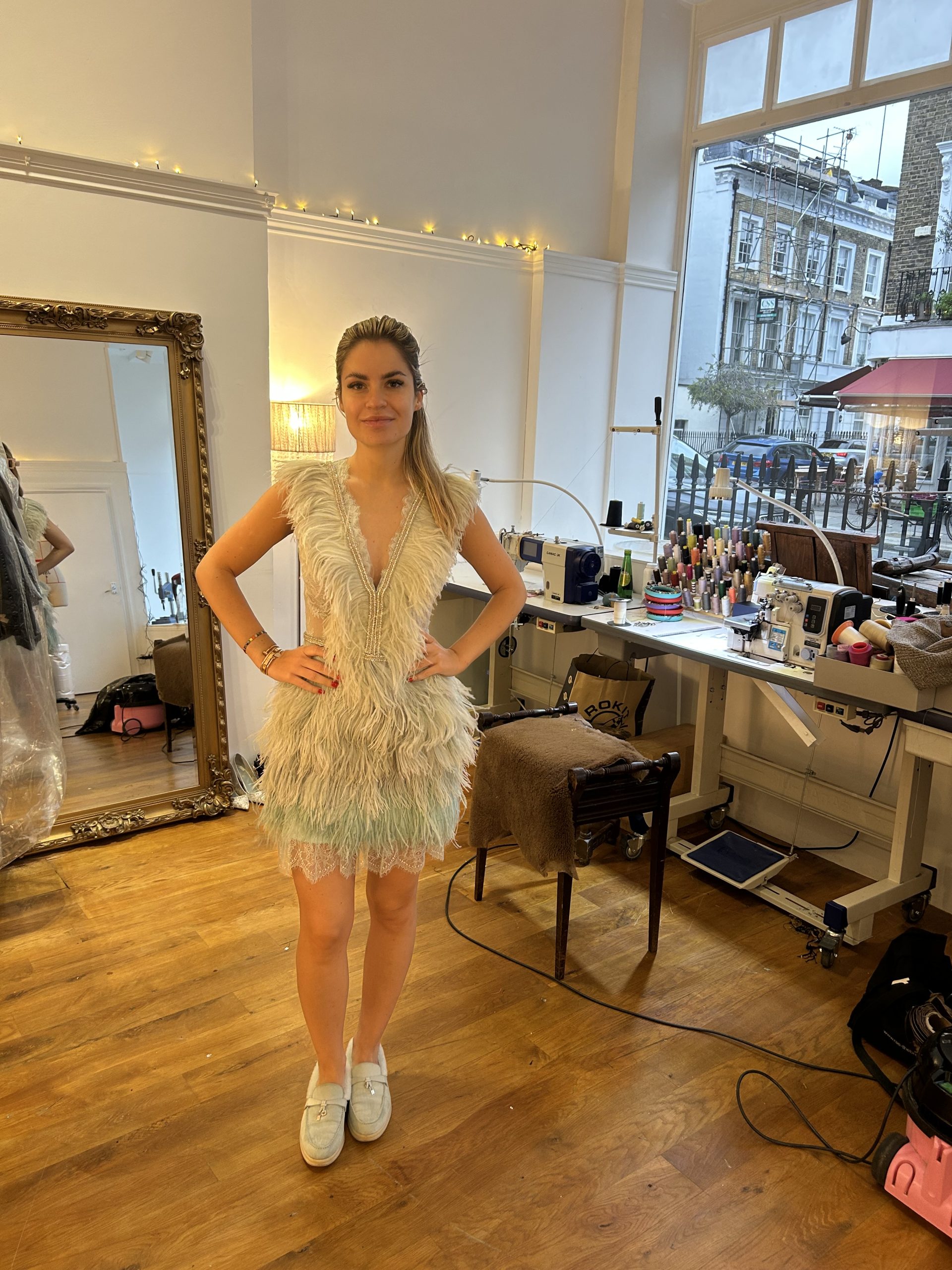 Bespoke pale blue feather mini dress with beaded neckline shown in a luxury alterations atelier.