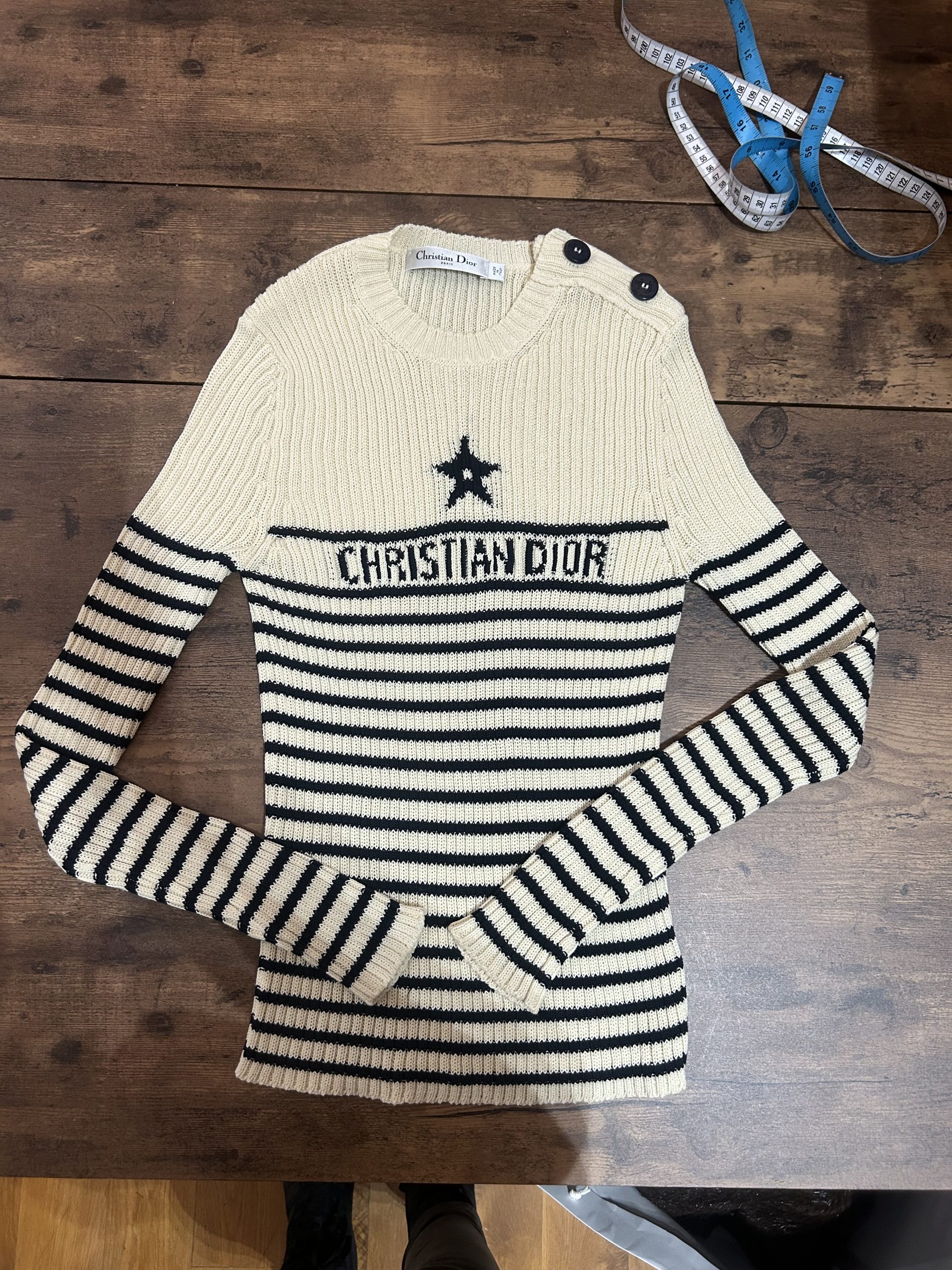 Christian Dior cream and navy striped knit jumper laid out for luxury alterations with a measuring tape.