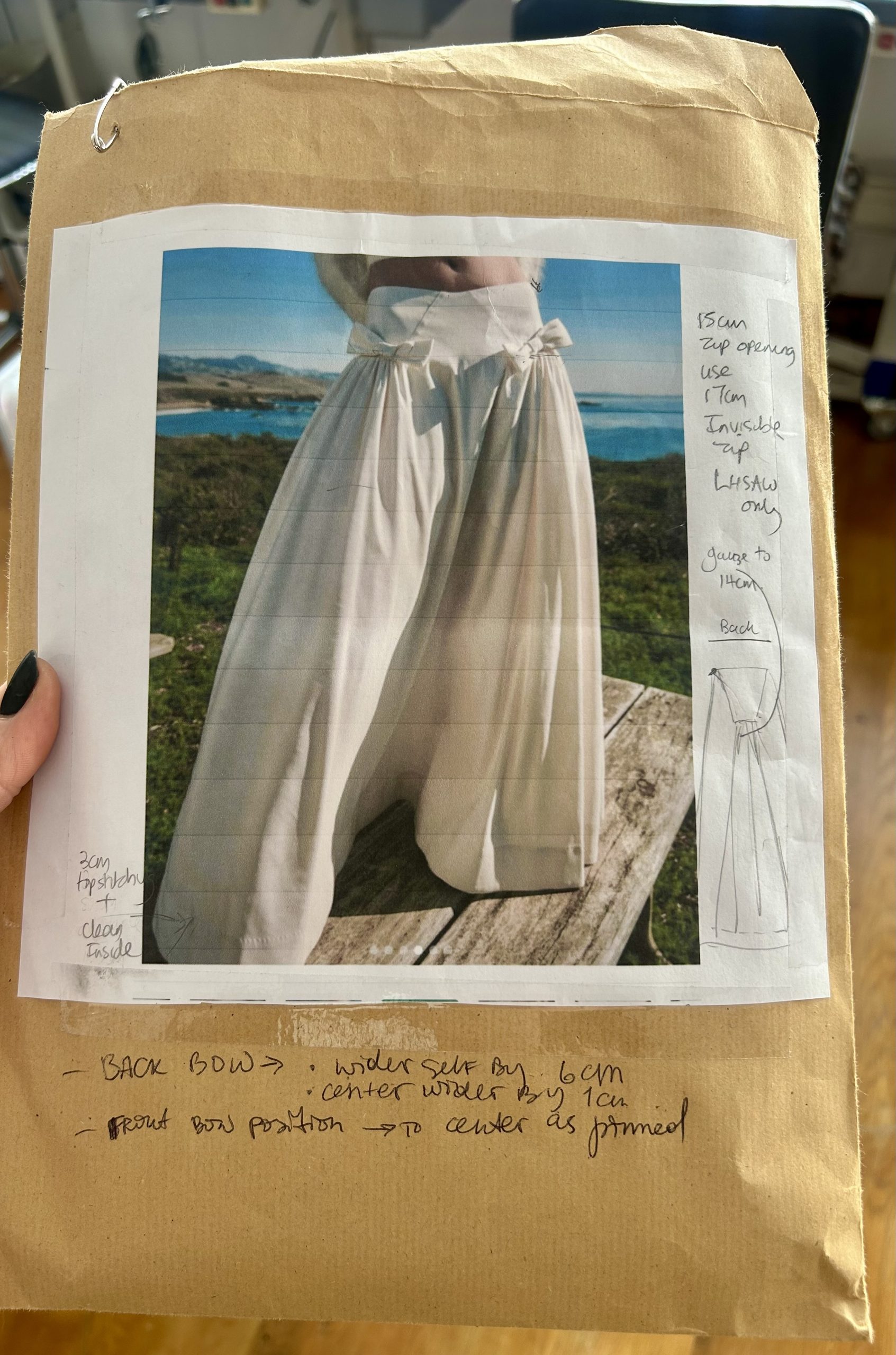 Handwritten construction notes on a design sheet for custom cream wide-leg trousers