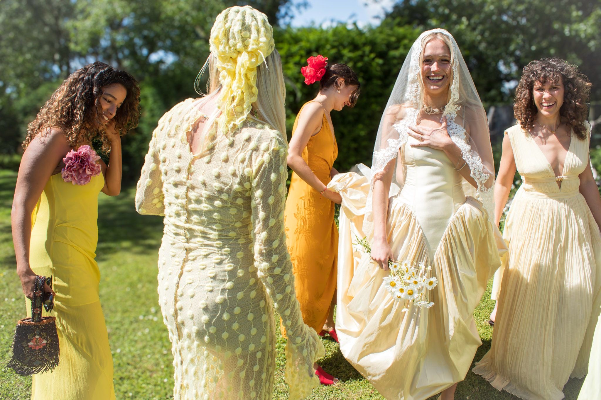 Bride in a ruched cream wedding dress with bridesmaids in mix-and-match yellow dresses
