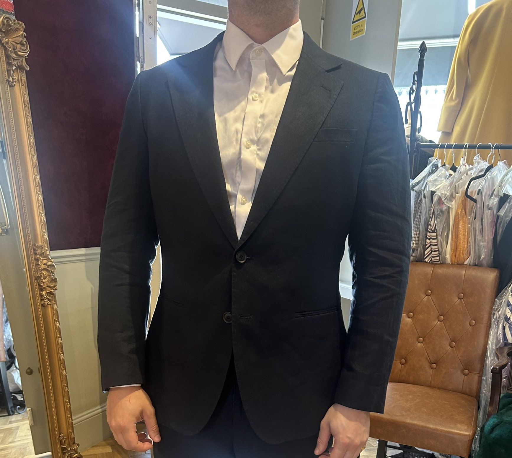 Close view of a navy single-breasted bespoke suit jacket over a white shirt in a tailoring atelier