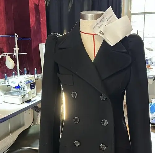 Bespoke black wool coat on a mannequin in the Altbes tailoring workshop